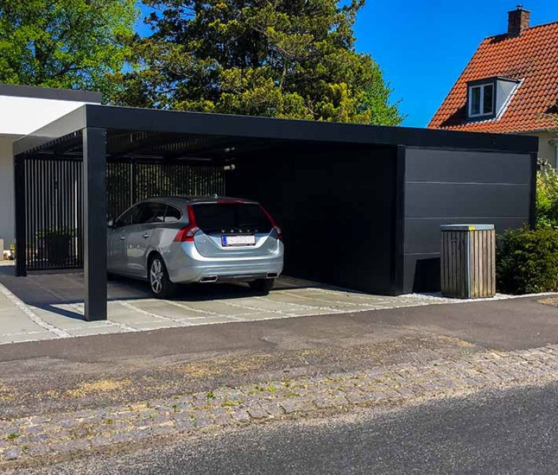 En sort carport med skur og træ lameller bagerst
